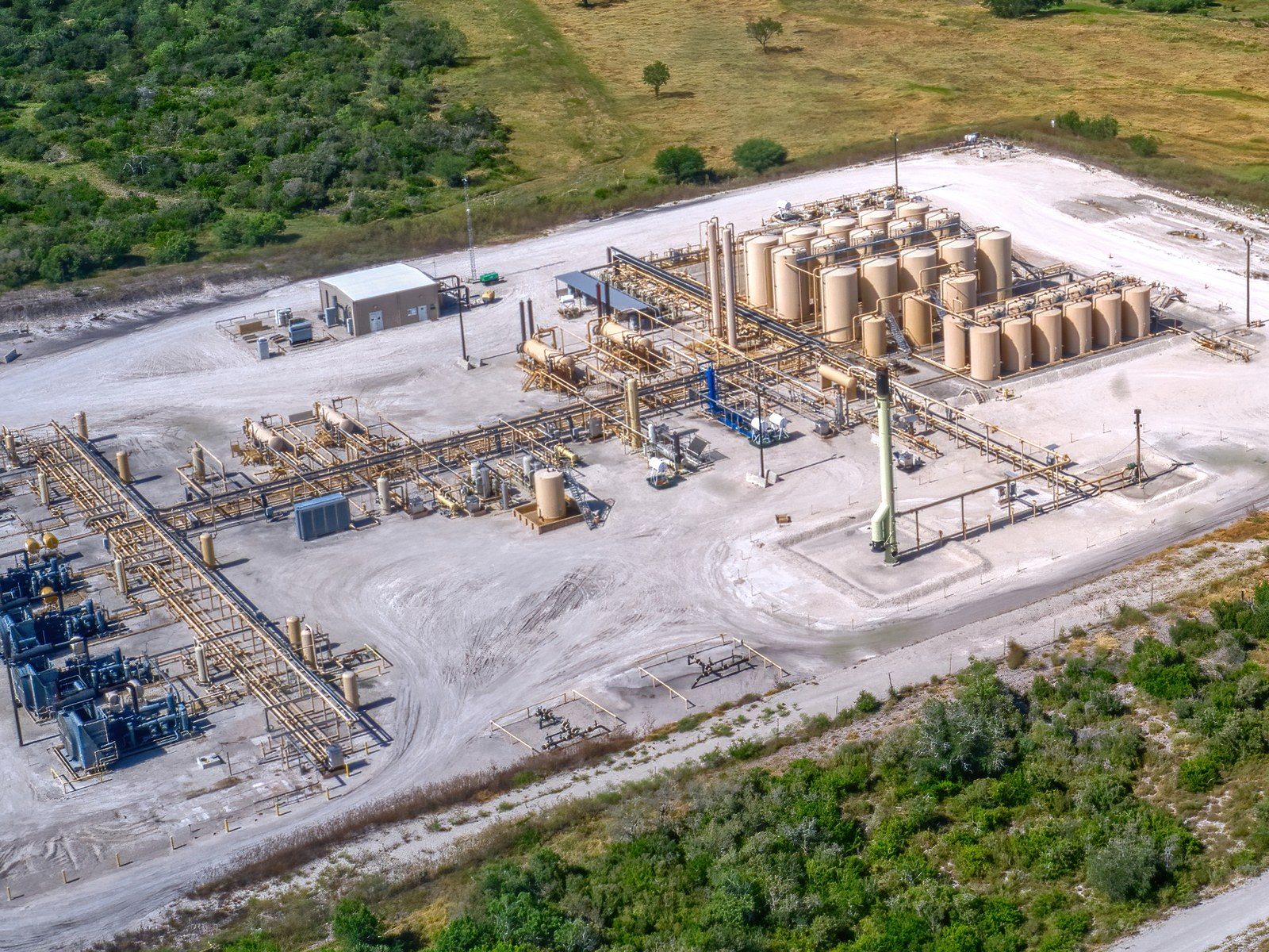 Aerial view of a gas processing plant with storage tanks, separators, and pipework